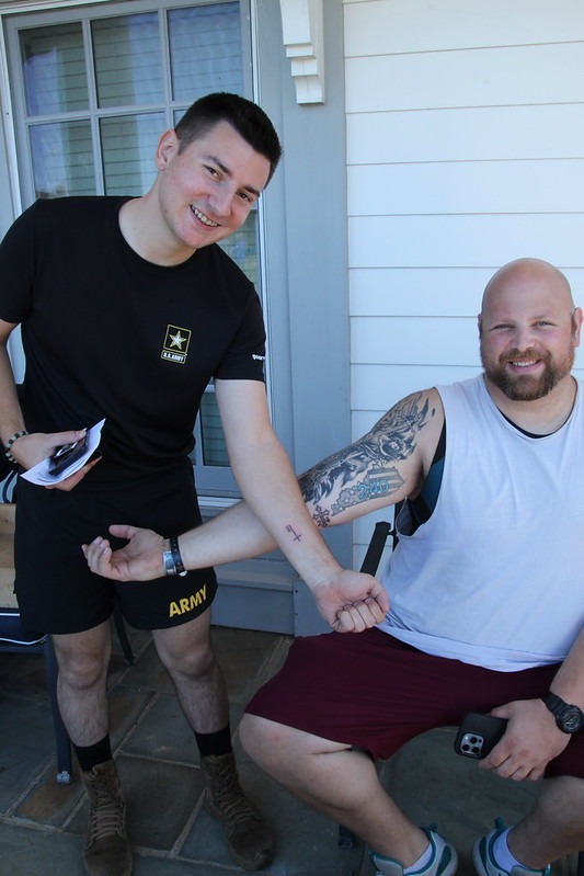 Veterans proudly displaying their fresh custom commemorative tattoos on Queenslake front porch