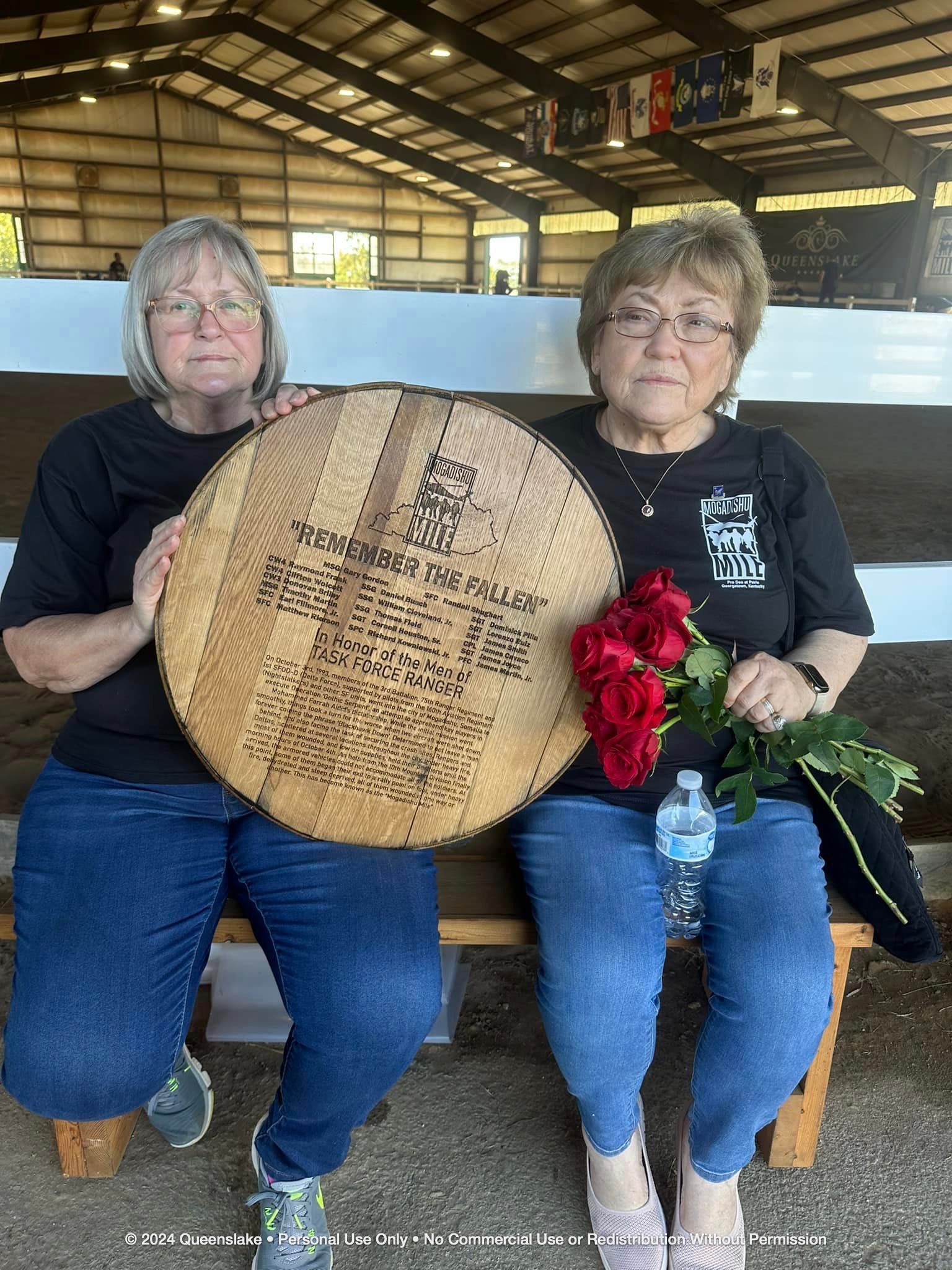 Willa Frank proudly holding the hand-carved bourbon barrel head honoring her late husband, SSG Raymond 'Frankie' Frank.