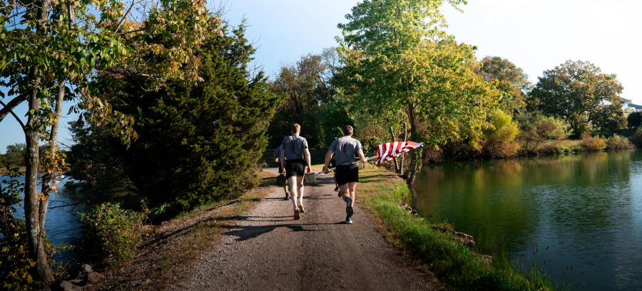 2026 Runners Carrying Flag Along Lake Causeway into Timber Trail